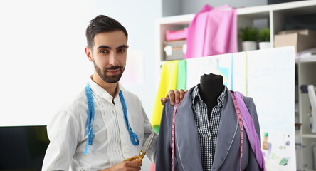 Male stylist designer holding scissors next to mannequin. Creation and tailoring of new fashion...