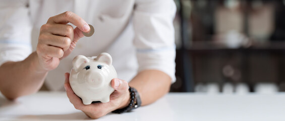 Man hand putting money coin into piggy for saving money wealth and financial concept.