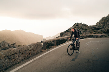 Young man looking at mountains while cycling on road