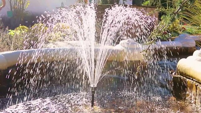 Fountain in the city park. Splashes of water shimmer in the sun. Small drops fly around. Decorative fountain. Decoration.