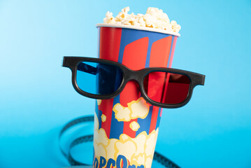 Movie clapper, pop corn, 3D glasses and film reel on blue background. Collage design