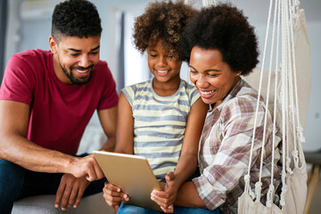 Happy african family having fun with device at home, black parents and child using digital tablet