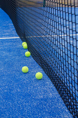 balls on a blue paddle tennis court with artificial grass