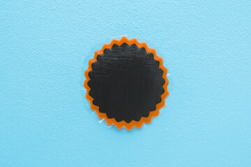 New dark black patch for car, bicycle or other transport tire hole repair on light blue table...