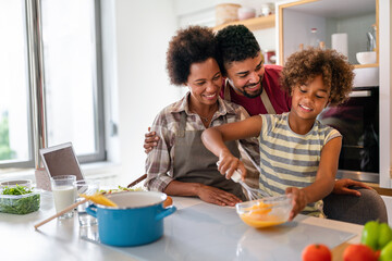 Happy african american family preparing healthy food in kitchen, having fun together on weekend - Powered by Adobe
