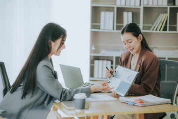 Portrait of two Asian businesswomen working together as a business team having a meeting to analyze data for a marketing plan.
