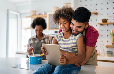 Happy african american family preparing healthy food in kitchen, having fun together on weekend