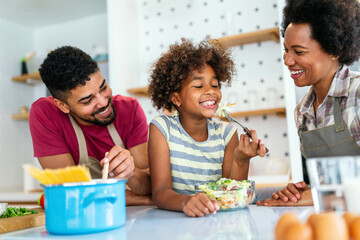 Happy black family in the kitchen having fun and cooking together. Healthy food at home.