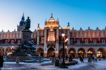 Krakow Christmas Market Square - before the sunset. Beautiful Sukiennice (Cloth Hall) and Adam Mickiewicz sculpture