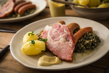 2 Portionen Oldenburger Grünkohl mit geräucherter Kohlwurst, Pinkel, Kassler Nacken, Kartoffeln, Senf, Petersilie auf Teller und Holz Hintergrund