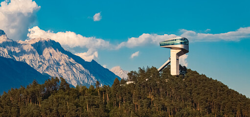 Alpine summer view with the famous Berg Isel Ski Jump Tower and the Nordkette mountains in the background near Innsbruck, Austria - obrazy, fototapety, plakaty