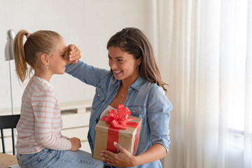A cheerful mother is excited to surprise her daughter with a big birthday present.