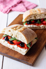 Ciabatta with cheese, tomatoes, sausage, olives and arugula. Sandwich. Italian food.