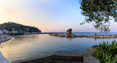 Townscape of Lacco Ameno at dusk in Ischia Island, Italy. View of the Fungo mushroom rock, a huge...