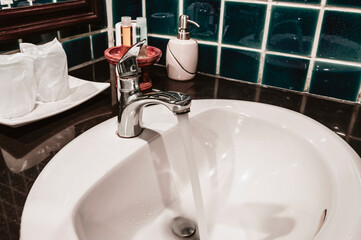 Faucet in a white sink in a bathroom with blue wall tiles