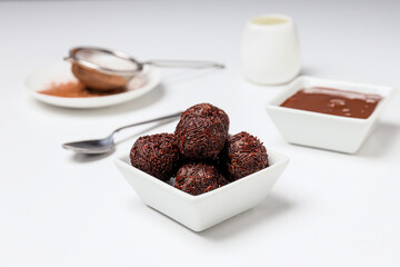 Brigadeiro and chocolate in bowls on white background, close up