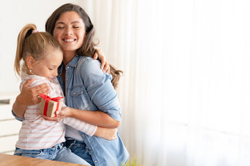 A sweet and adorable little girl pleasantly surprises her mother with a thoughtful gift on Mother's Day.