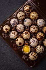 Raw quail eggs in a plastic box on a dark concrete background