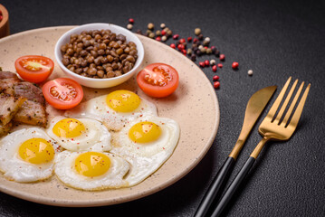 Delicious nutritious breakfast of fried quail eggs, bacon, legumes and cherry tomatoes