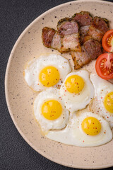 Delicious nutritious breakfast of fried quail eggs, bacon, legumes and cherry tomatoes