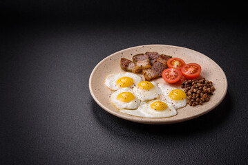 Delicious nutritious breakfast of fried quail eggs, bacon, legumes and cherry tomatoes