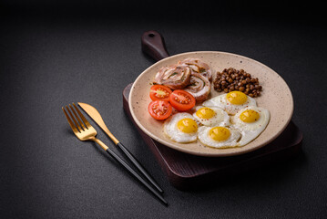 Delicious nutritious breakfast of fried quail eggs, bacon, legumes and cherry tomatoes