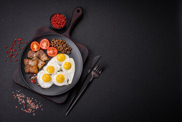 Delicious nutritious breakfast of fried quail eggs, bacon, legumes and cherry tomatoes