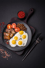 Delicious nutritious breakfast of fried quail eggs, bacon, legumes and cherry tomatoes