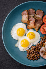 Delicious nutritious breakfast of fried quail eggs, bacon, legumes and cherry tomatoes