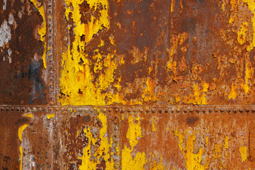 beautifully rusted rivetted sheet metal with leftovers of yellow paint texture and full-frame flat...
