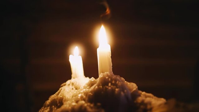 A close-up of two burning candles, the wax from which flows down solidifying. Shooting in slow motion