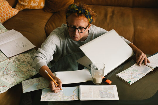 High angle view of senior woman planning trip on map at home
