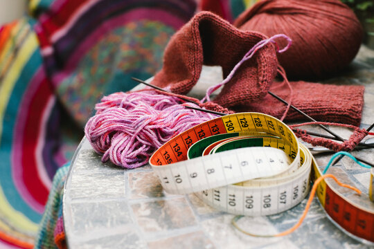 Tape measure with wool and knitting needles on table