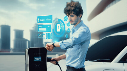 Businessman check EV car battery status on smartwatch hologram while recharge from charging station...