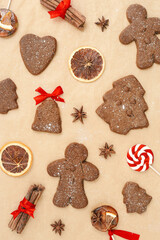 Christmas gingerbread cookies or biscuits on baking paper, winter seasonal traditional bakery with spices, dry orange, cinnamon sticks, anis, candy. Top view sweet food pattern, new year flat lay