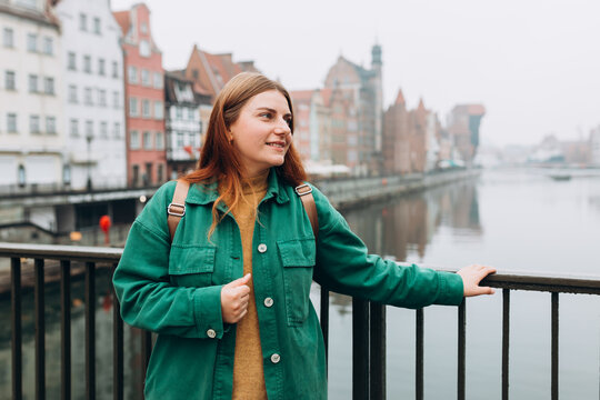 Attractive young female tourist is exploring new city. Gdansk old town and famous Zuraw crane, A happy beautiful woman is standing near Motlawa river