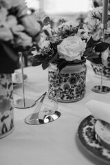 Assortment of flowers arranged in a vase resting on a table in grayscale