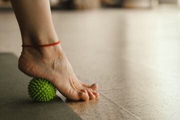 Close - up of the legs of a woman performing gymnastic exercises to correct flat feet during ball...