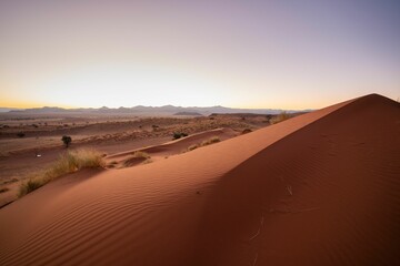 Fototapeta na wymiar Serene landscape of dunes silhouetted against the backdrop of a setting sun