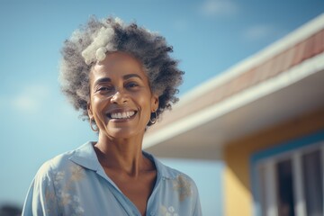 Close-up portrait of a beautiful senior African American woman in home clothes smiling happily. Cheerful retired black lady with curly grey hair against the background of her cozy house.