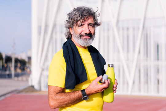 happy senior sports man smiling looking at camera and drinking water during training, concept of healthy and active lifestyle in middle age, copy space for text