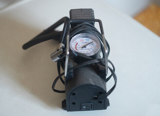 close up of a mini compressor with pressure gauge on white table called 