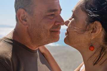 Closeup portrait of happy middle aged couple enjoying romantic moment on the beach. Mature man and...