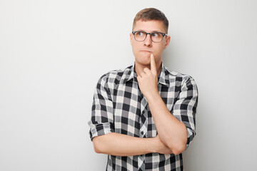 Portrait of clever man in shirt touching chin thinks doubts chooses isolated on white studio background with copy space