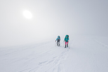 Fototapeta na wymiar winter activity. Two women walking in snowshoes in the snow, winter hiking, two people in the mountains in winter.