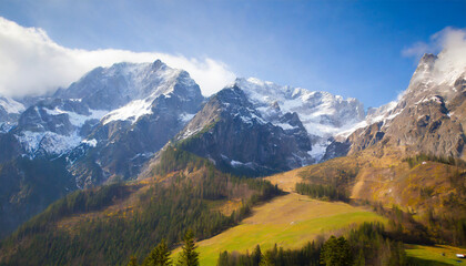 Fototapeta na wymiar Alpine mountains in winter covered with snow, green meadows