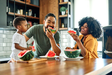 child family kitchen food boy son father mother watermelon fruit slice summer organic meal fun preparing healthy diet eating home black - Powered by Adobe