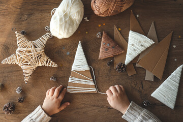 Child makes Christmas decoration from yarn - obrazy, fototapety, plakaty
