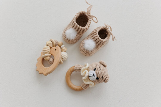 Newborn baby booties and wooden rattles on a white background.