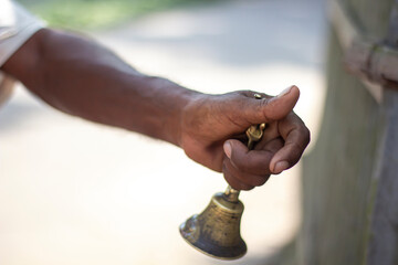 A man holding a brass bell and blurred background